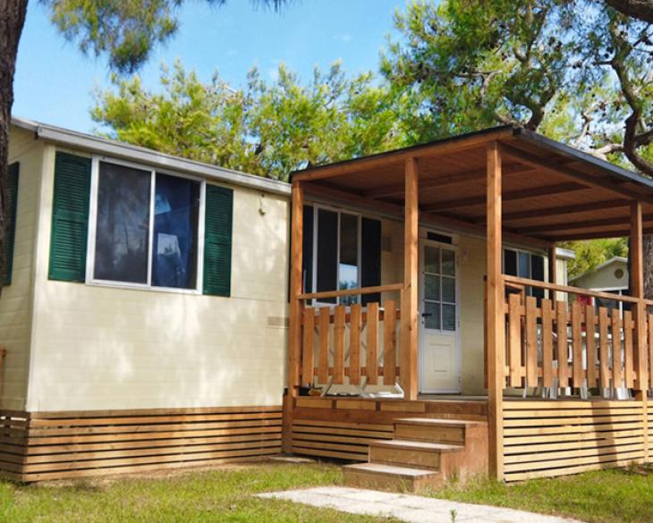 Maison mobile avec porche en bois, entourée de nature.