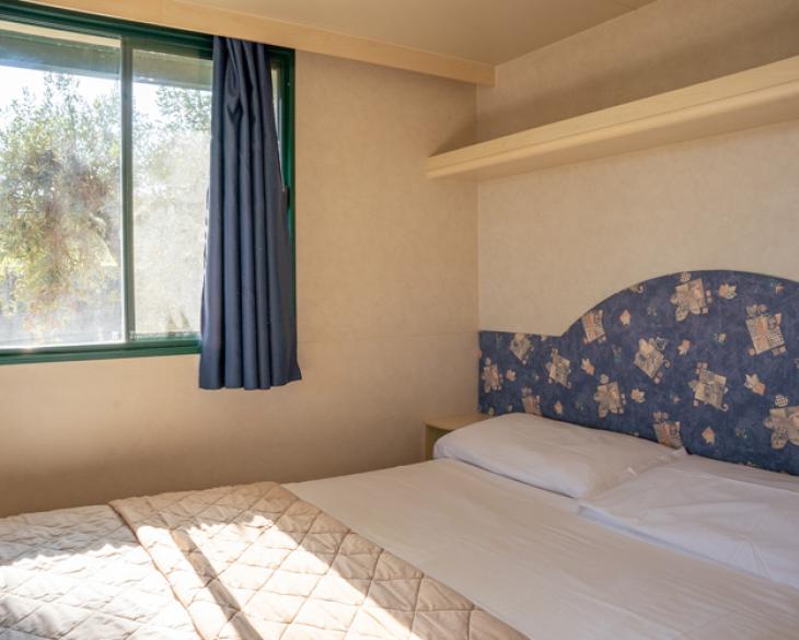 Chambre simple avec fenêtre et lit double.