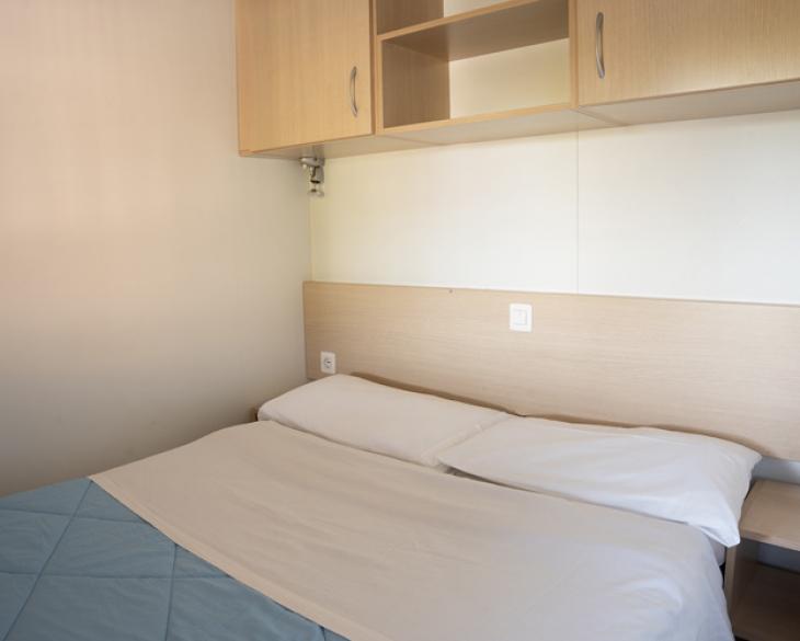 Chambre simple avec lit double et placard mural.