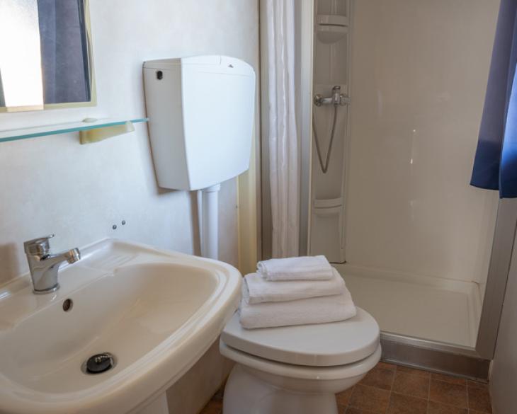 Salle de bain compacte avec douche, lavabo et WC.