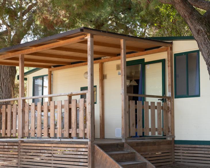 Bungalow en bois entouré de nature avec une véranda.