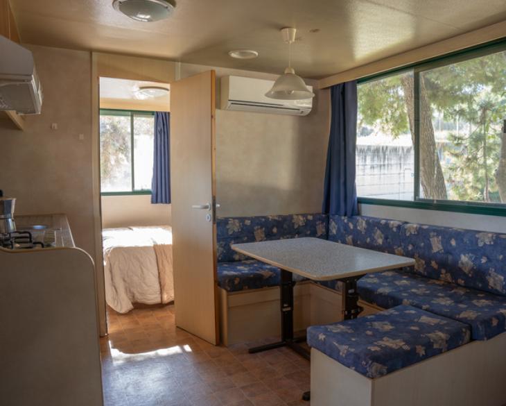 Intérieur d'une maison mobile avec cuisine, table et lit.
