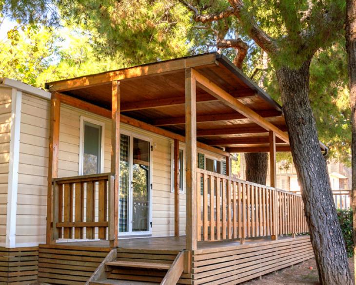 Maison mobile avec porche en bois entourée de nature.