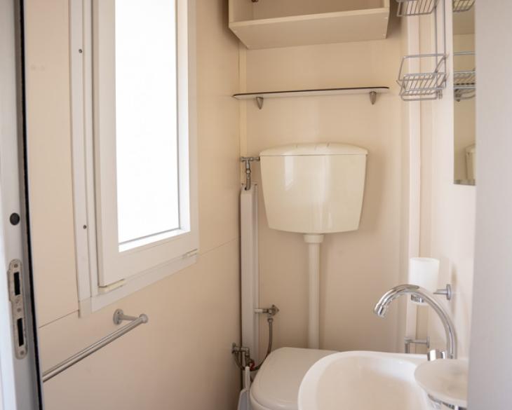 Salle de bain compacte avec fenêtre, lavabo et WC.