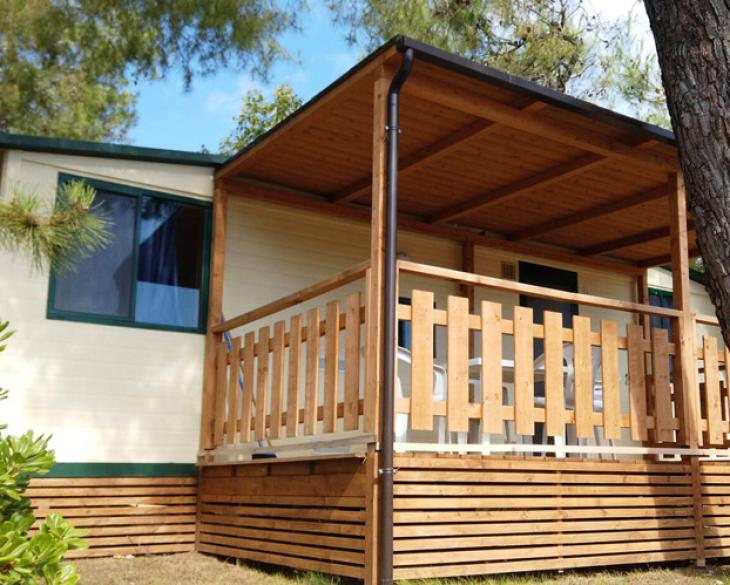 Maison mobile avec porche en bois entourée de nature.