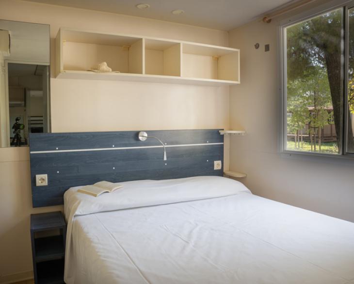 Chambre moderne avec lit double et fenêtre lumineuse.