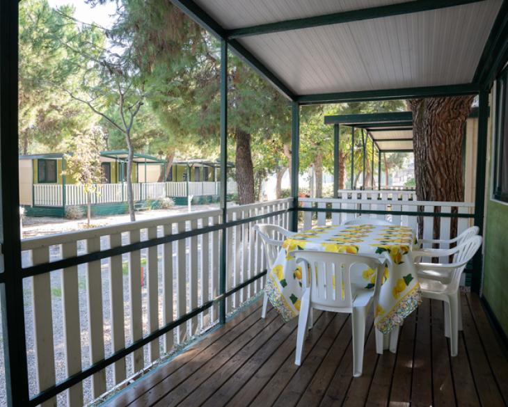 Véranda avec table et chaises dans un camping parmi les arbres.