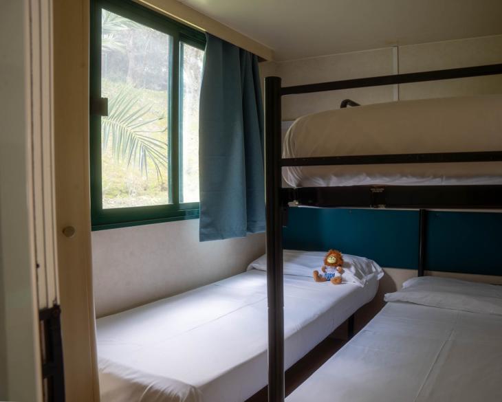 Chambre avec lits superposés et peluche, vue sur jardin.
